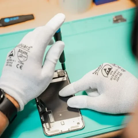 Tekniker åbner en mobiltelefon på værkstedet for at undersøge den indvendigt